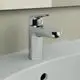 Chromfarbene Armatur von Ideal Standard mit Hebelgriff und seitlichem Auslauf, montiert auf einer weißen Waschbeckenfläche, vor einer beige Wand.